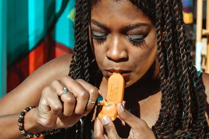 Mulher fuma maconha com cachimbo de plástico.