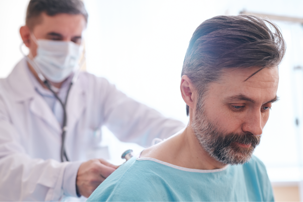 Doctor in surgical mask using stethoscope while listening to patients lungs with stethoscope