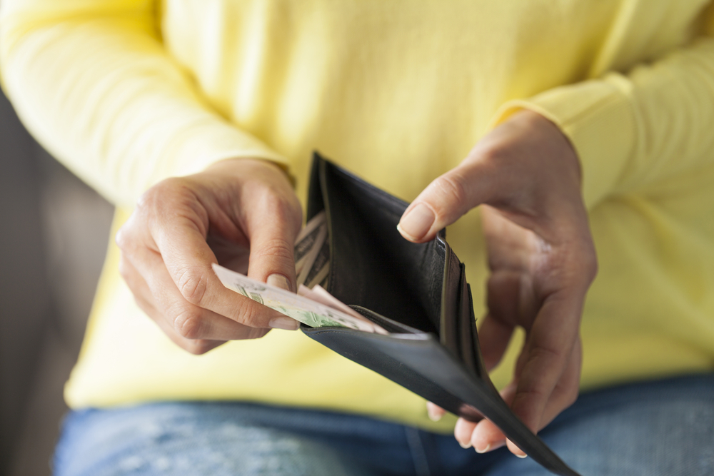 A woman looks at how much money she has in her wallet